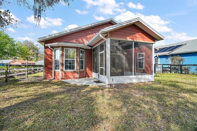 rear view of house with a sunroom, a lawn, and fence