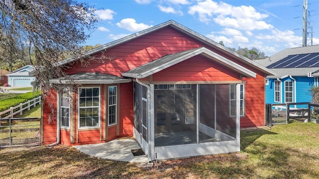 rear view of property featuring a sunroom, roof with shingles, fence, and a yard