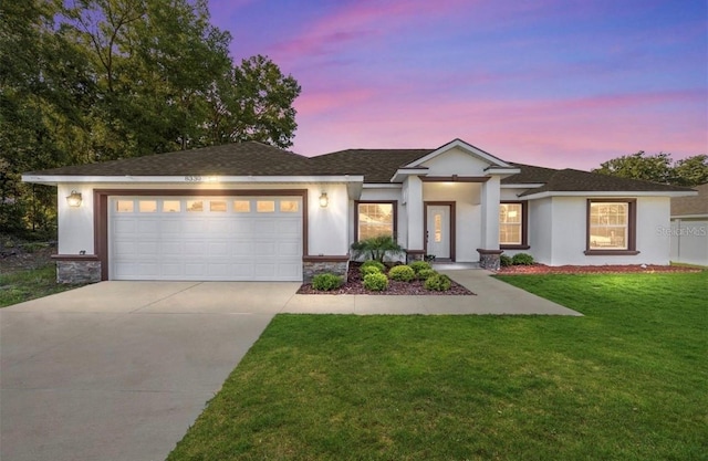 view of front of home featuring an attached garage, driveway, stone siding, stucco siding, and a front lawn