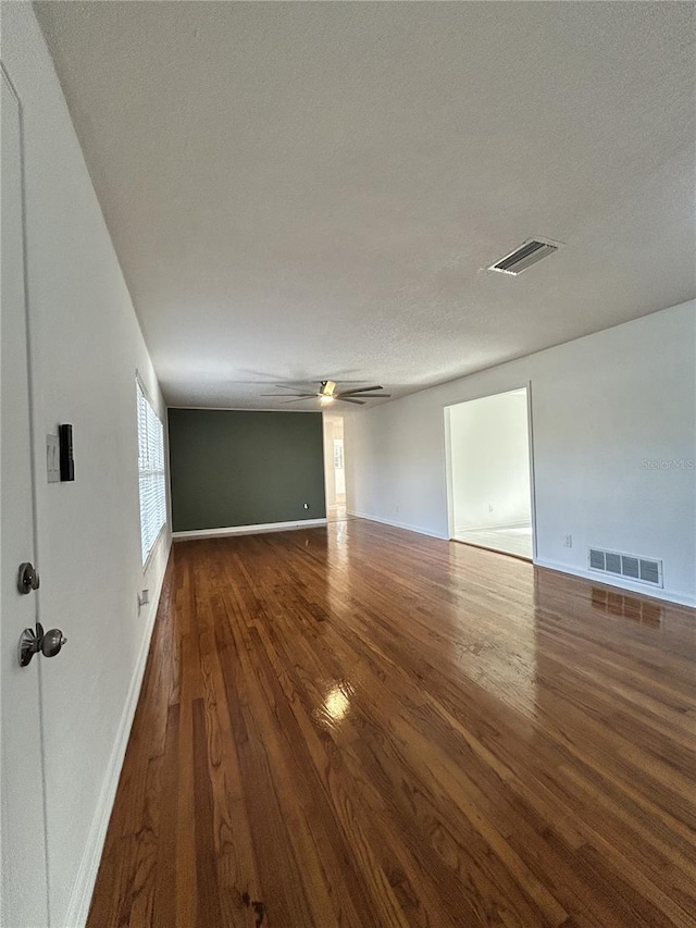 unfurnished room featuring visible vents, ceiling fan, baseboards, and wood finished floors