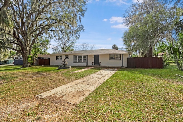 single story home with stucco siding, a front yard, and fence