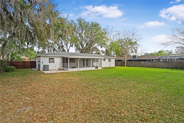 rear view of property featuring central AC unit, a fenced backyard, a sunroom, stucco siding, and a lawn