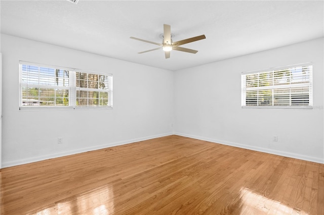 empty room with baseboards, a healthy amount of sunlight, a ceiling fan, and light wood finished floors