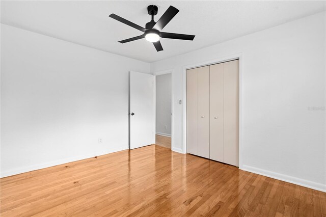 unfurnished bedroom with a closet, a ceiling fan, baseboards, and wood finished floors