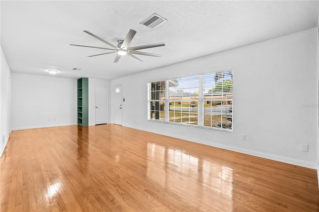 unfurnished living room with baseboards, visible vents, light wood-style flooring, ceiling fan, and a textured ceiling