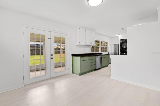 kitchen with green cabinets, dishwasher, light wood-type flooring, stacked washer and clothes dryer, and french doors