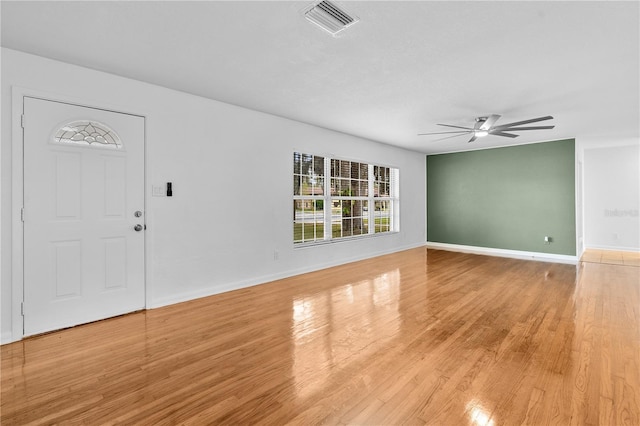 unfurnished living room with visible vents, light wood-style flooring, baseboards, and a ceiling fan