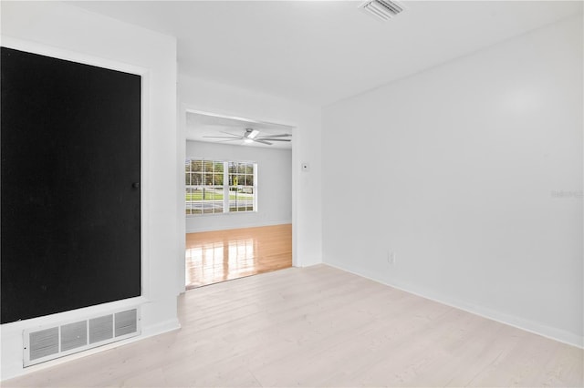 spare room featuring a ceiling fan, wood finished floors, and visible vents