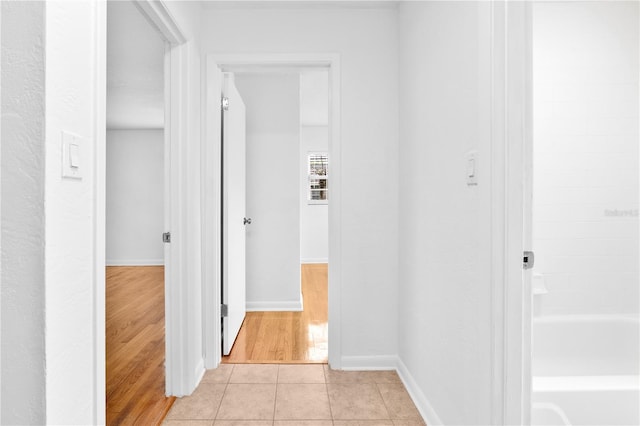 corridor with baseboards and light tile patterned flooring
