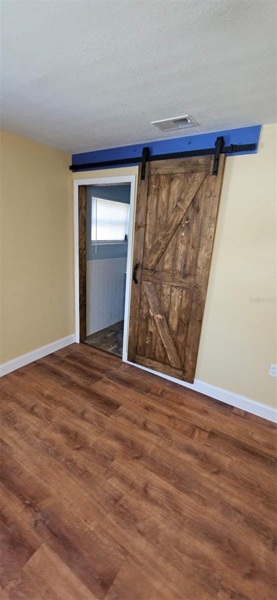 31 Roosevelt Blvd, Beverly Hills, FL 34465 - empty room featuring visible vents, a barn door, baseboards, and wood finished floors
