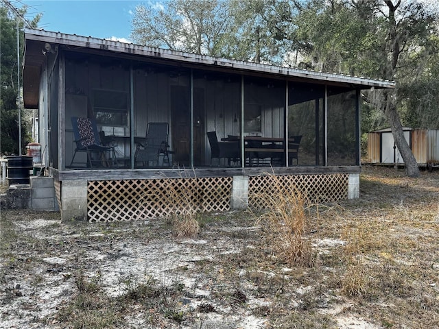 back of house featuring a sunroom, a storage shed, cooling unit, and an outbuilding