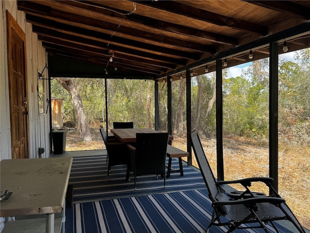 unfurnished sunroom with a forest view and beam ceiling