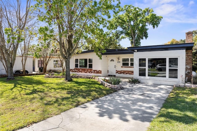 ranch-style house featuring brick siding, a front lawn, and a chimney