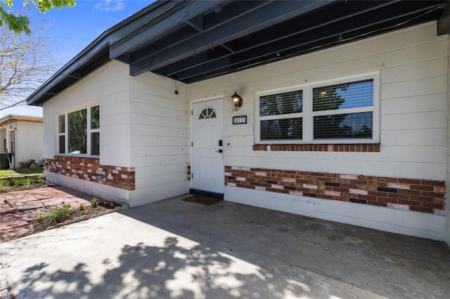 entrance to property featuring brick siding and a patio