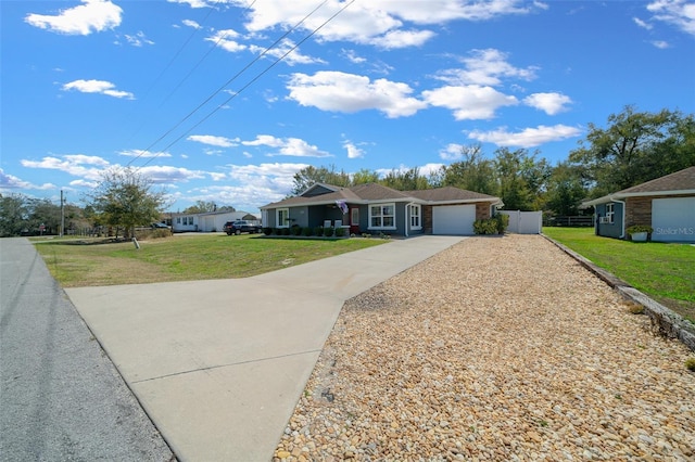 ranch-style house featuring an attached garage, fence, concrete driveway, and a front yard