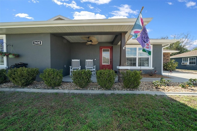 property entrance with covered porch, ceiling fan, and stucco siding