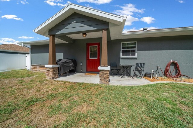 exterior space featuring a patio area, a lawn, and stucco siding