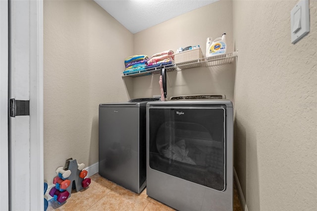 laundry room with laundry area, baseboards, washer and clothes dryer, a textured wall, and light tile patterned flooring