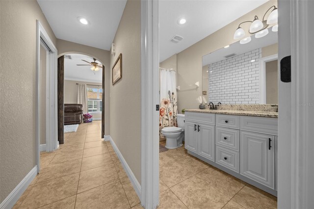 bathroom with toilet, a sink, visible vents, baseboards, and double vanity