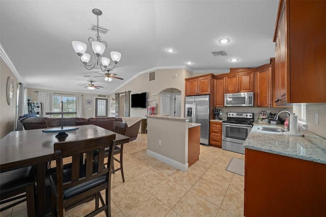 kitchen featuring stainless steel appliances, a sink, visible vents, a center island, and brown cabinetry