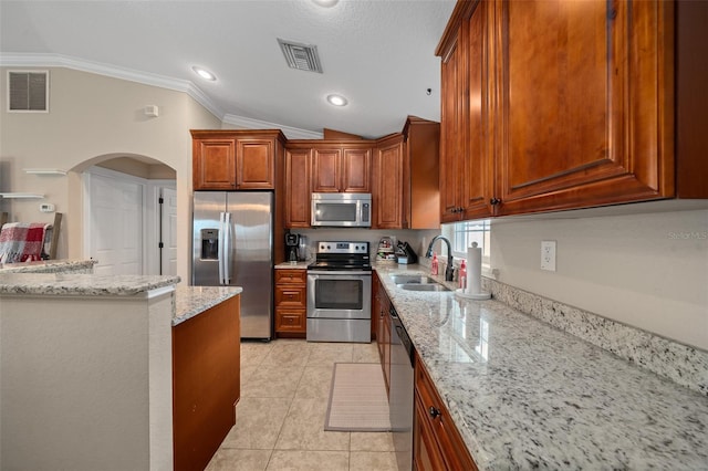 kitchen featuring stainless steel appliances, light stone counters, a sink, and visible vents