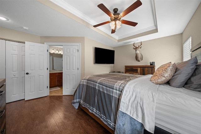 bedroom featuring a raised ceiling, connected bathroom, dark wood finished floors, ceiling fan, and crown molding