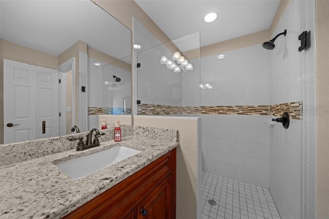 bathroom featuring tiled shower and vanity