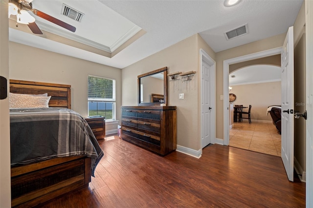 bedroom featuring ornamental molding, arched walkways, visible vents, and wood finished floors