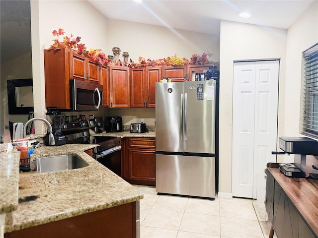 kitchen featuring light tile patterned floors, light stone counters, stainless steel appliances, and a sink