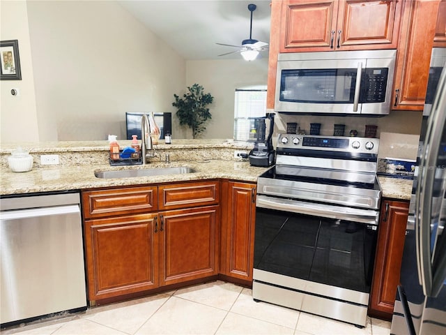 kitchen with light stone counters, light tile patterned floors, appliances with stainless steel finishes, a ceiling fan, and a sink