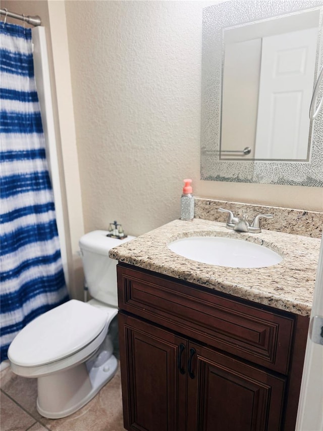 bathroom with a textured wall, toilet, a shower with curtain, tile patterned floors, and vanity