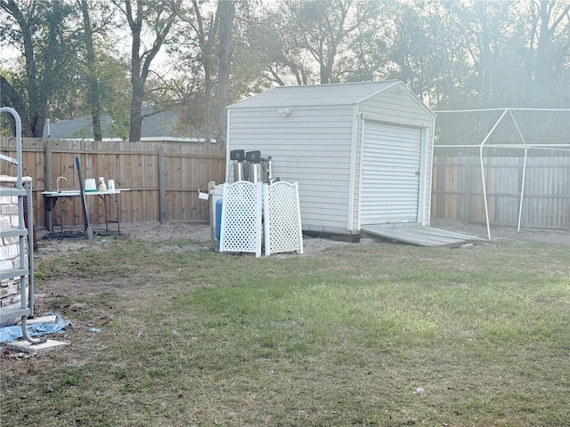 view of yard featuring a garage, a fenced backyard, a shed, and an outbuilding