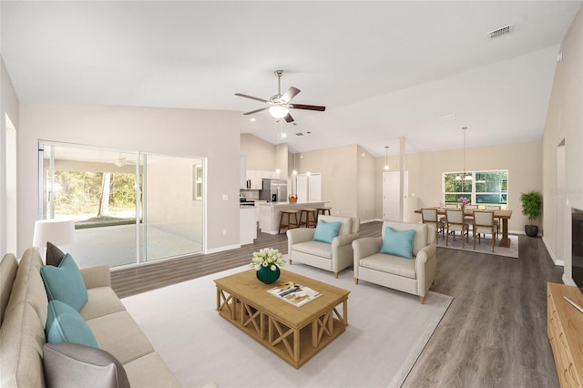 living room with baseboards, visible vents, vaulted ceiling, and wood finished floors