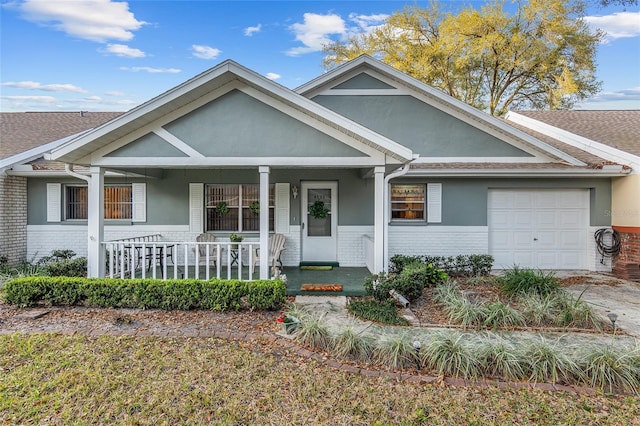 view of front of home featuring an attached garage, brick siding, a porch, and stucco siding