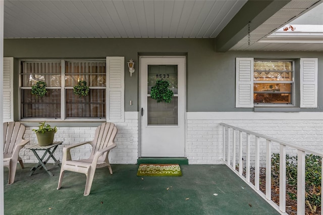 doorway to property with covered porch and brick siding