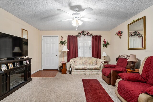 carpeted living area featuring a ceiling fan and a textured ceiling