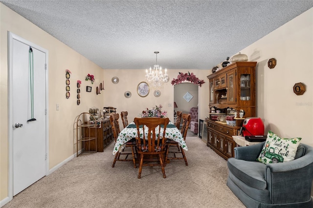 dining area with light colored carpet, a textured ceiling, baseboards, and an inviting chandelier