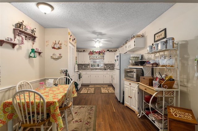 kitchen featuring a sink, white cabinets, backsplash, dark wood-style floors, and stainless steel microwave