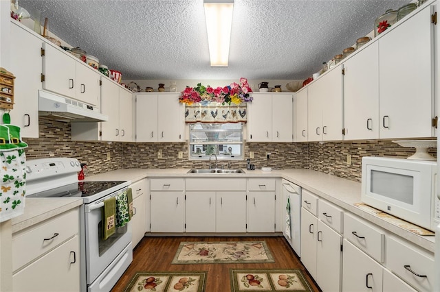 kitchen featuring white appliances, dark wood-type flooring, light countertops, under cabinet range hood, and a sink