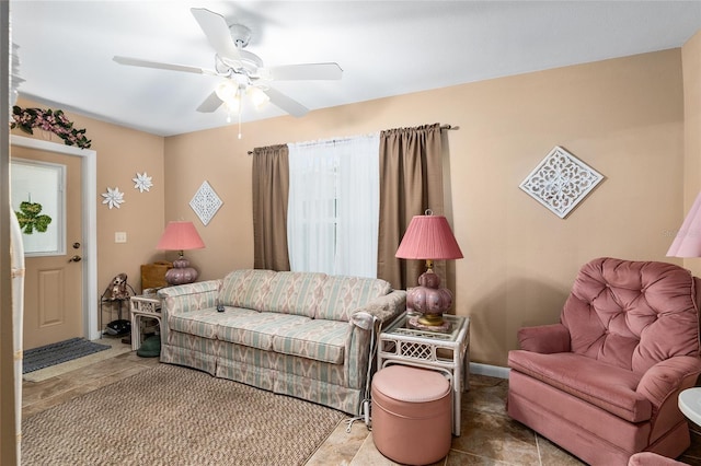 living area with ceiling fan and baseboards