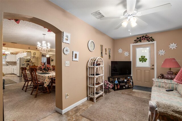 living room featuring arched walkways, ceiling fan with notable chandelier, visible vents, and baseboards