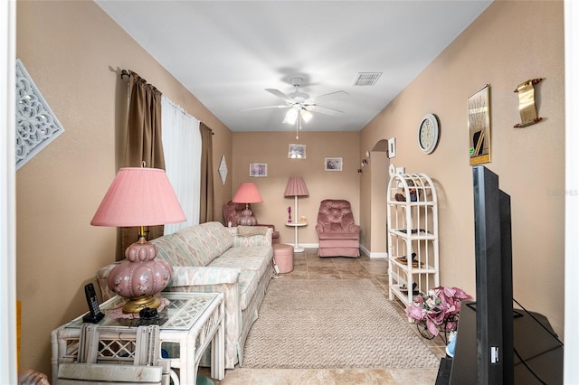 tiled living room featuring a ceiling fan, visible vents, and baseboards