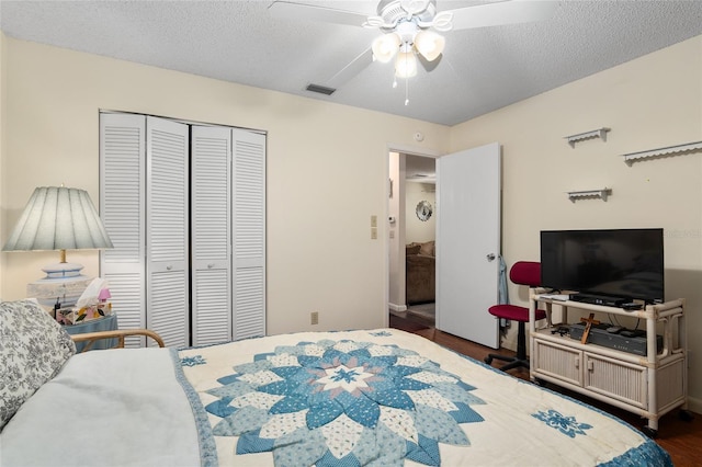 bedroom featuring a closet, visible vents, a ceiling fan, a textured ceiling, and wood finished floors