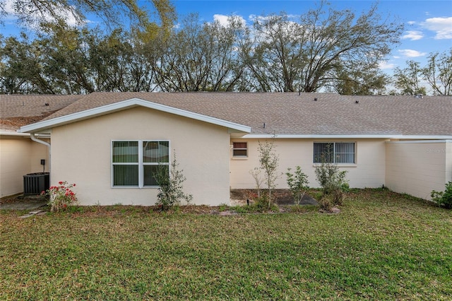 view of side of home featuring roof with shingles, central AC unit, a lawn, and stucco siding
