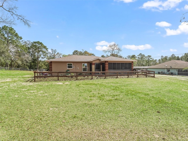 back of house with a sunroom, fence, stucco siding, and a yard