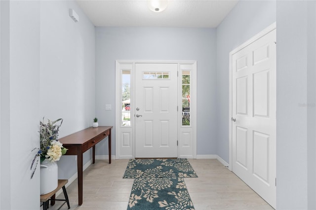 foyer with light wood-style flooring and baseboards