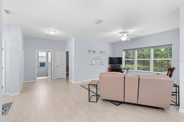 living area with baseboards, visible vents, and light wood-style floors