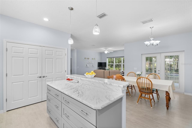 kitchen with light wood finished floors, a center island, visible vents, and french doors