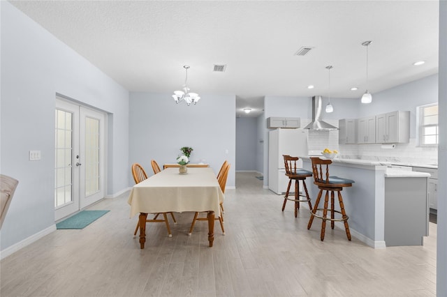 dining area with light wood-style floors, baseboards, visible vents, and french doors