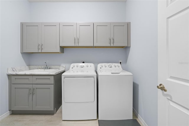 washroom featuring cabinet space, light wood-style floors, a sink, washer and dryer, and baseboards